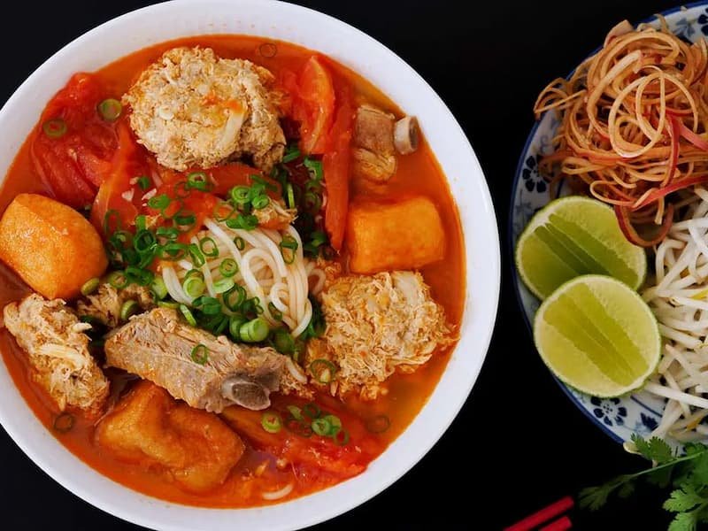 Complete bun rieu cua meal with condiments and herbs in Hanoi