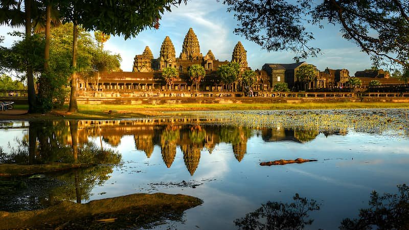 Angkor Wat temple bathed in golden sunlight under a clear blue sky during Cambodia’s dry season.
