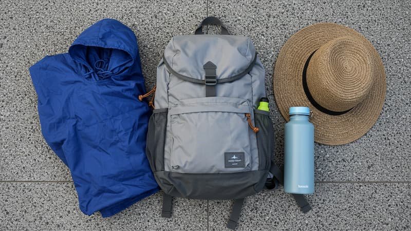 A lightweight backpack with a poncho, hat, and water bottle