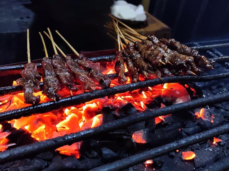 Traditional charcoal-grilled goat meat preparation at Quan Bui Bao Khanh in Hanoi