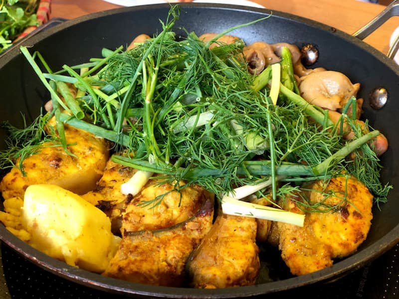 Traditional Chả Cá Lã Vọng fish dish being prepared tableside in Hanoi