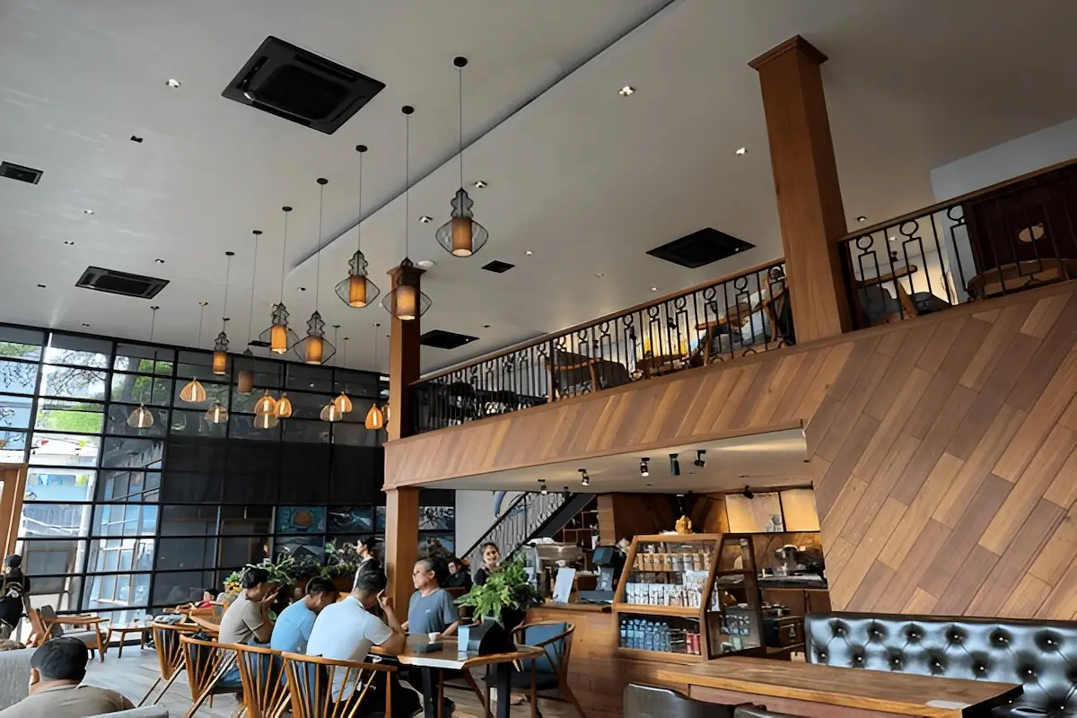 Professional coworking space in Cambodia with communal tables, individual workstations, and tropical plant decor, where digital nomads can work for 50% less than comparable spaces in Thailand