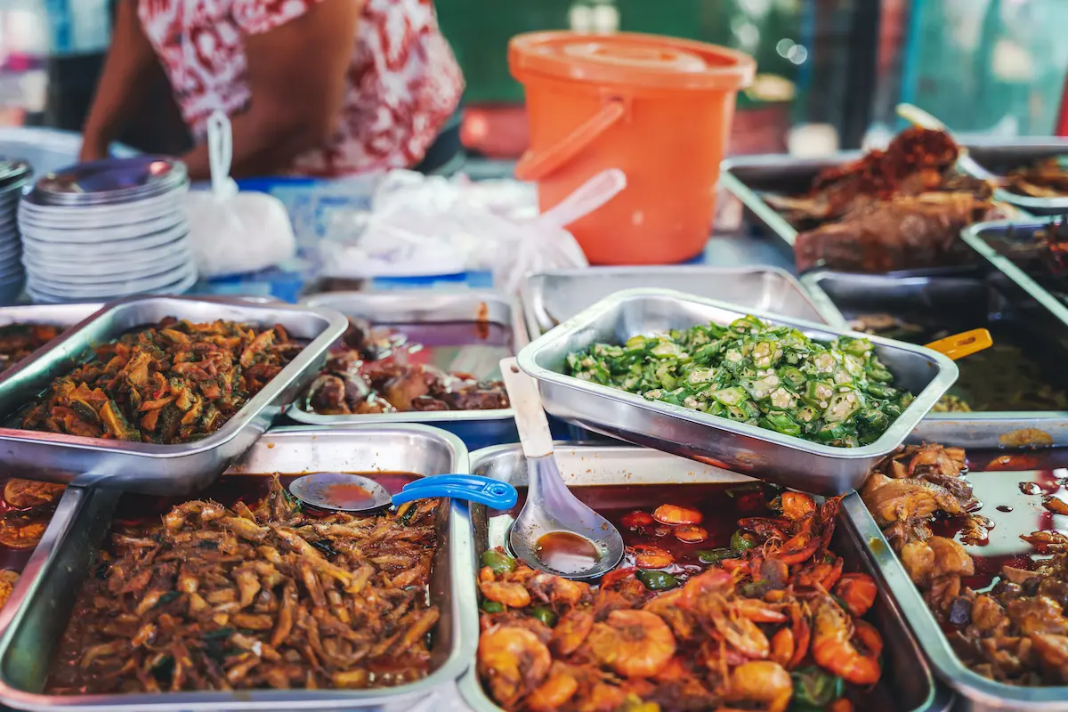 Cambodian street food stall serving rice dishes with colorful curry options for under $2, exemplifying why Cambodia emerges as Southeast Asia's budget travel hotspot