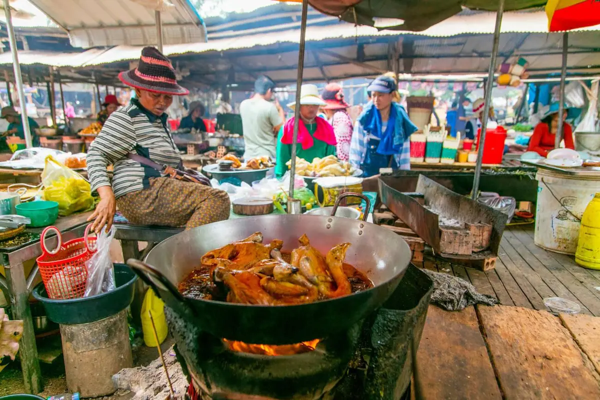 Cambodian street food chef cooking in a large wok at an outdoor market, preparing affordable local dishes that make Cambodia Southeast Asia's budget travel hotspot