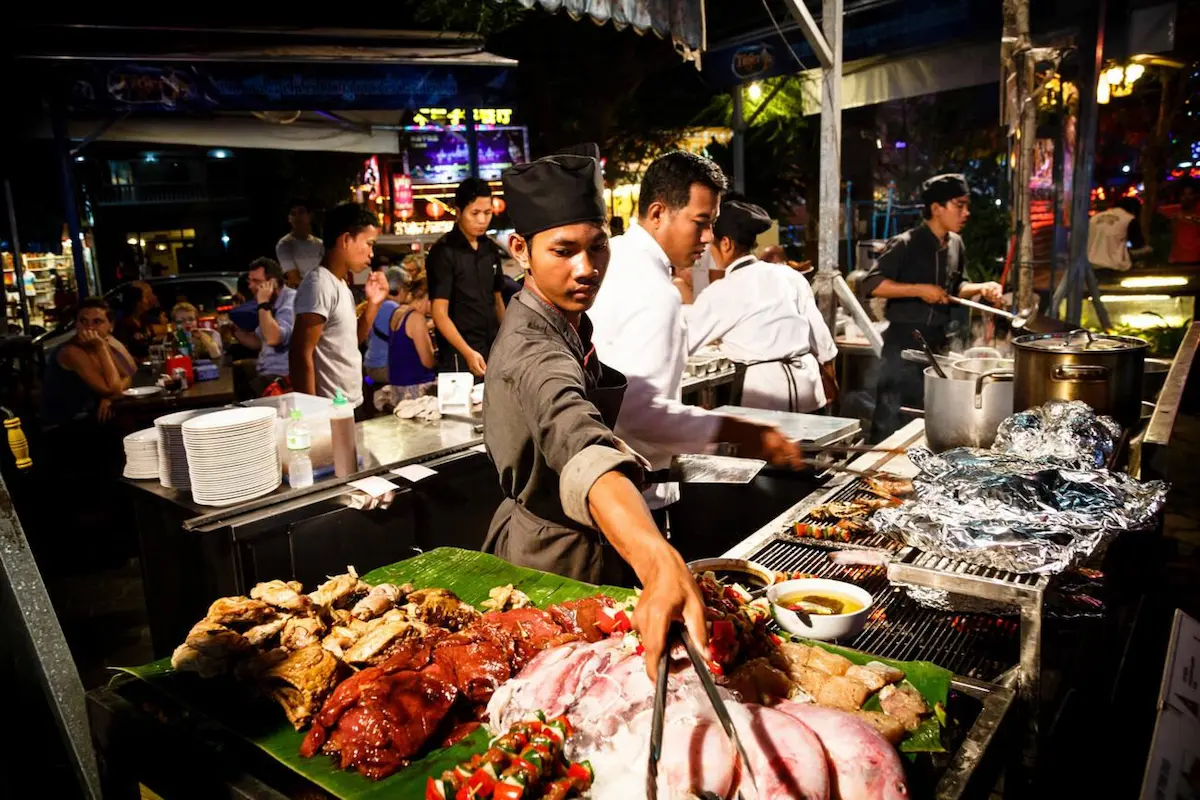 Seafood and Meat vendor at a lively Cambodian street food market where fresh catches are prepared for just $3-4, demonstrating the country's budget travel value