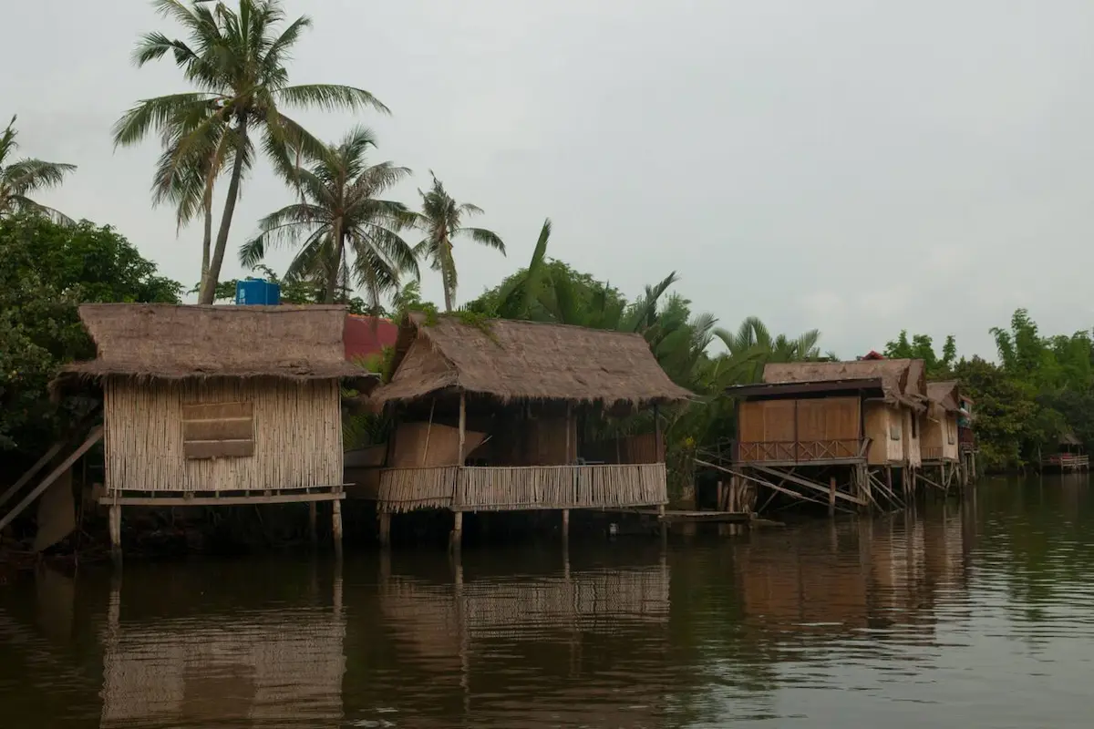 Traditional wooden bungalows overlooking Kampot's peaceful river at sunset, with rooms starting at just $15 per night