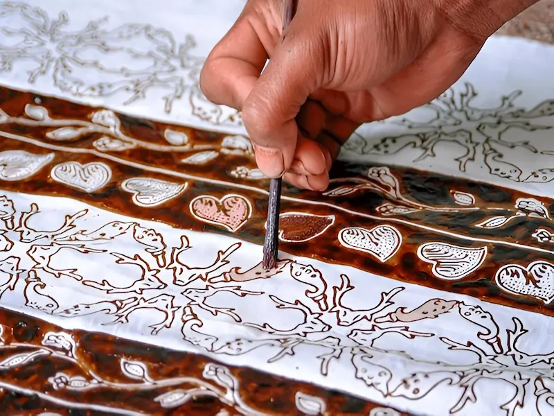 Traditional batik artisan demonstrating the wax-resist dyeing technique in Jakarta