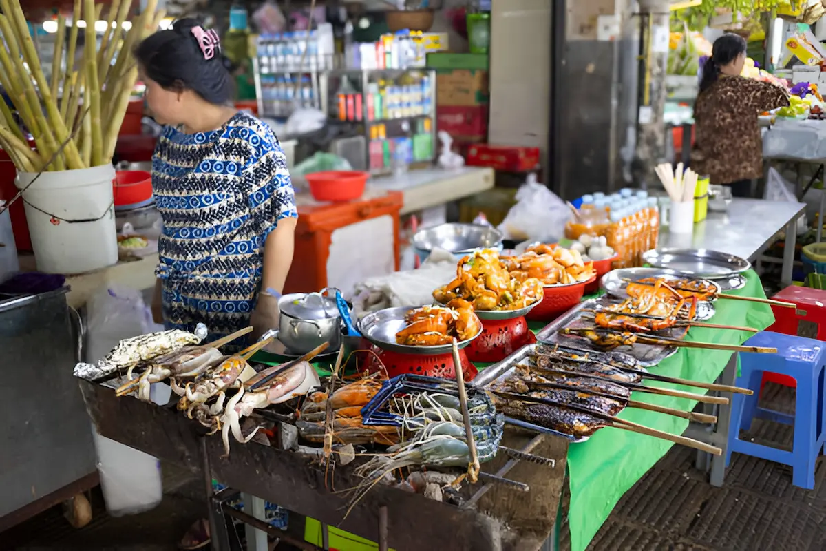Fresh seafood grilling at a local beach market on Koh Rong where budget travelers can enjoy freshly caught fish and seafood for $3-5 per meal, significantly cheaper than similar beachfront dining in Thailand