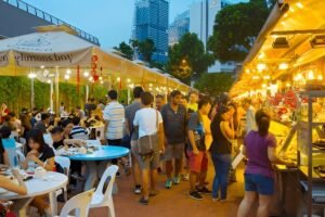 Crowd enjoying the best time to visit Singapore for street food at a bustling hawker centre under neon lights.