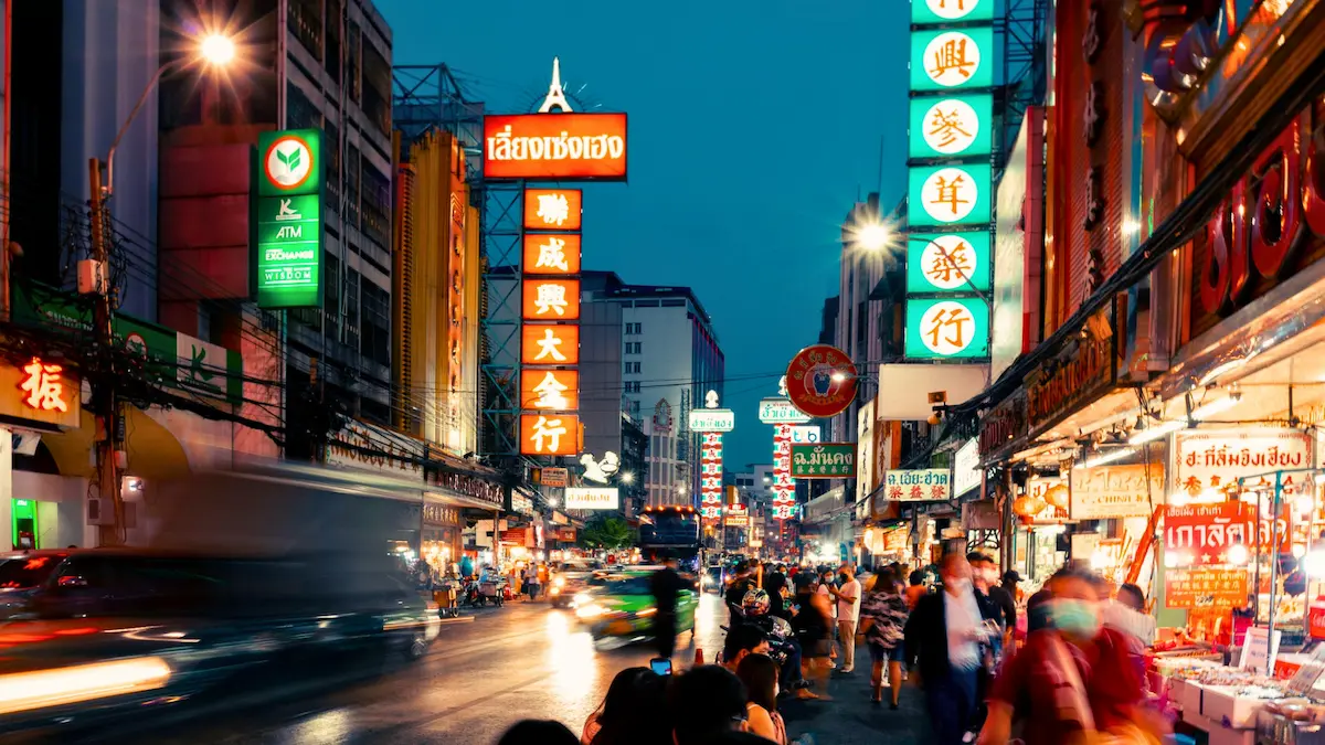 Tourists walking in Bangkok street with caution sign overlay
